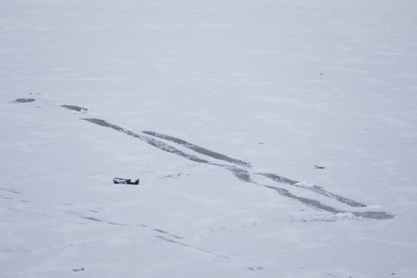 Abdrücke von zwei schlitternden Füßen im dünnen Schnee auf dem dünnen Eis vom Karpfenteich. 