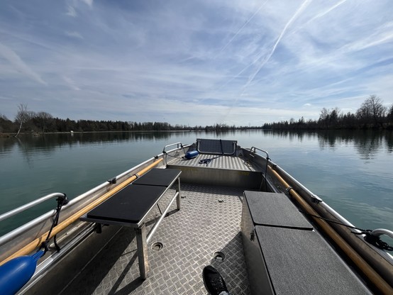 Interior of a pontoon boat on a calm river with clear skies.