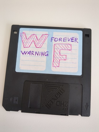 floppy disk with a big pink W and F and the smaller text warning forever in purple written on the label