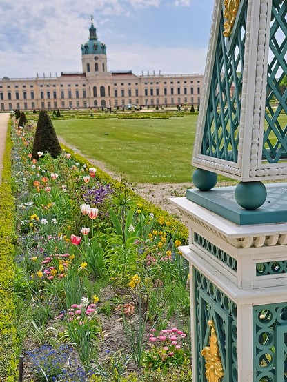 Blick auf den intensiv gepflegten Teil des Schlossparks. Im Hintergrund das Schloss Charlottenburg. Im Vordergrund linear angelegte Beete mit Tulpenbewuchs.