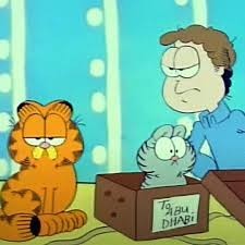 Bild aus der Garfield Trickserie zeigt garfield, eine graue Katze im Karton mit der Aufschrift „To ABU DHABI“ und John, der Garfield böse ansieht 
