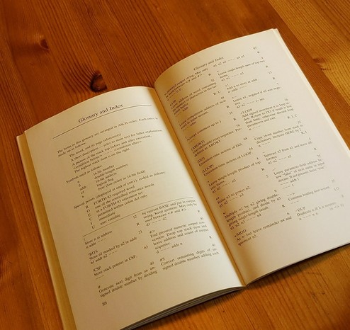 Zwei aufgeschlagene Seiten eines Buch-Glossars, das die Liste und Erklärung der Worte eines FORTH enthält