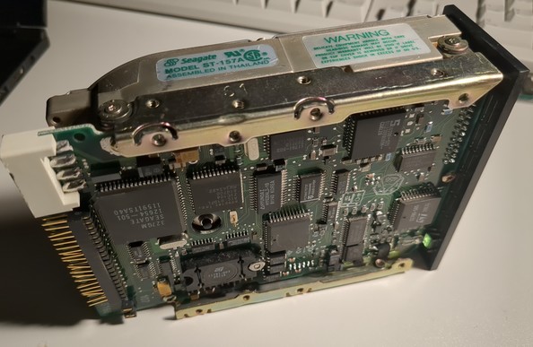 the hard disk laying on it's side. on the visible side is a seagate sticker with the model number, on the exposed bottom a PCB with lots of ICs