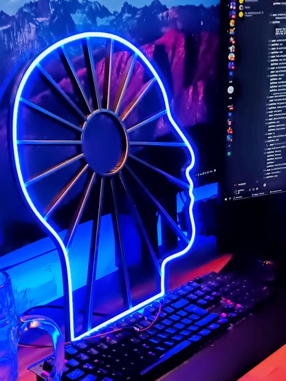 Blue led neon light in the shape of a human head side profile, with a circle in its center and rays pointing outside from it.