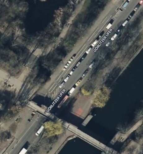 Satellitenbild des Görlitzer Ufer vor dem Umbau. Links und rechts der Autostraße parken Autos auf asphaltierten Parkplätzen.