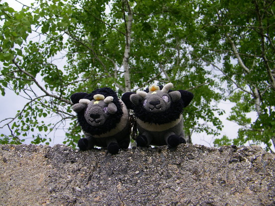 Two mini plush goats atop a "stone" monument.