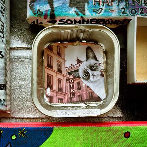 A collage inside a tin container, featuring a building with a 