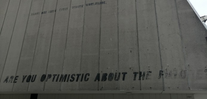 A stenxil graffito on a sad concrete wall. It says 