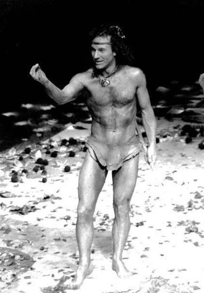 A black and white image of a young Patrick Stewart, with hair on his head, and very little clothing (a loincloth).