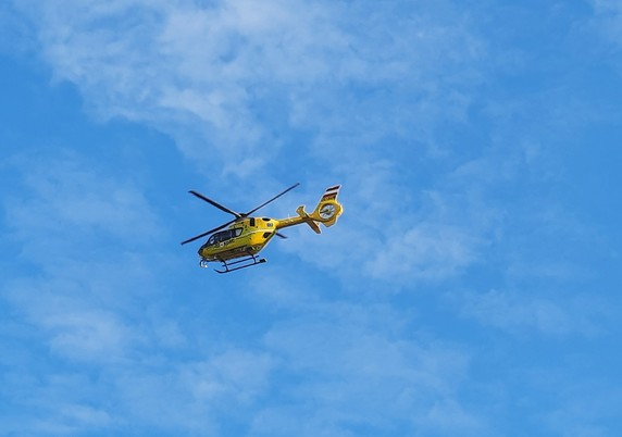 Gelber Rettungshubschrauber vor blauem Himmel mit leichten Wolken