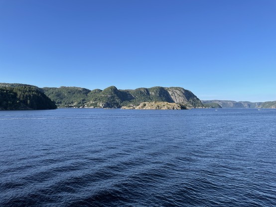 Blick auf einen Fjord, Berge, Wasser, klarer Himmel.