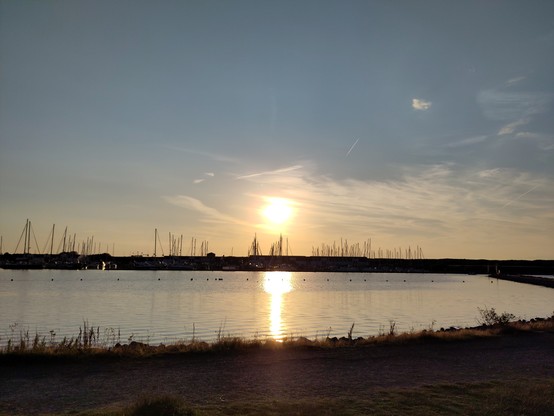 Ein Sonnenuntergang über dem Wasser. Im Hintergrund Boots-Masten.