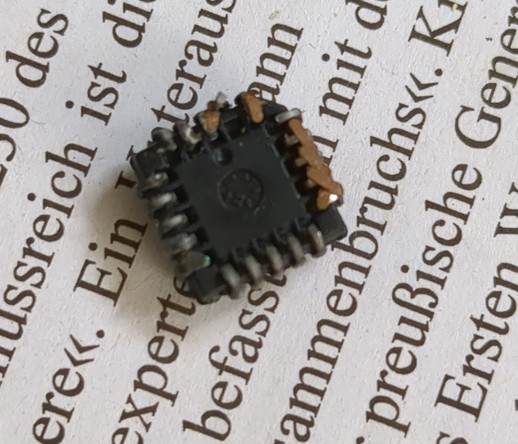 the same chip on it's back. the legs are curled up as if it was a dead spider. on two sides there are still parts if the pcb attached to the legs