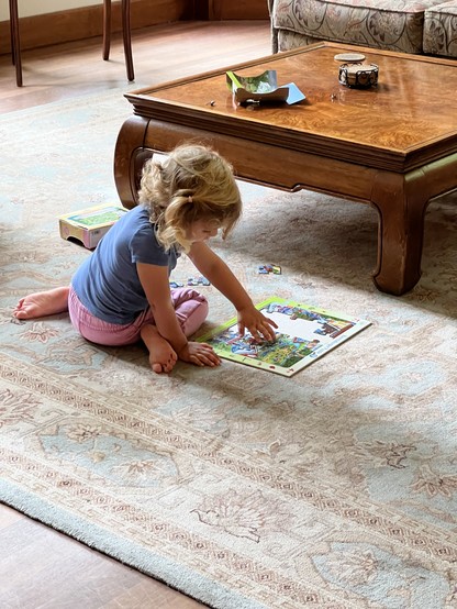 A child doing a jigsaw puzzle on the living room. 