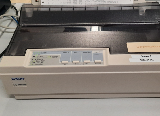An old EPSON LW-300+II dot matrix printer with a sticker for danger reports in german.