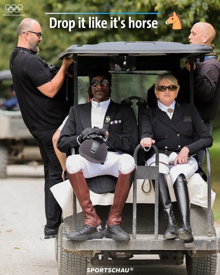 Das Bild zeigt zwei Personen in formeller Reitbekleidung, die auf einem kleinen Fahrzeug sitzen, vermutlich ein Golfcart. Die Person auf der linken Seite ist dunkelhäutig und trägt eine Sonnenbrille, einen schwarzen Hut und schwarze Handschuhe. Die Person auf der rechten Seite ist hellhäutig und trägt ebenfalls eine Sonnenbrille. Beide tragen weiße Reithosen und schwarze Jacken. 

Hinter ihnen stehen zwei Männer, die das Fahrzeug bedienen oder begleiten. Über dem Bild steht der Text 