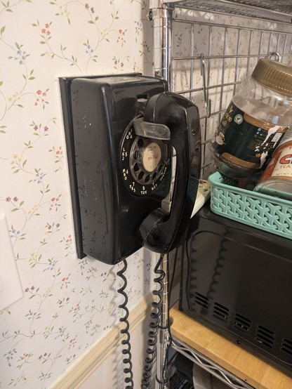 black rotary phone mounted on a wall