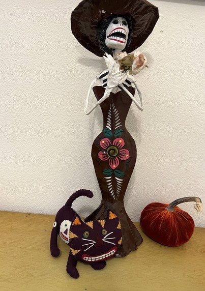 A skeletal Katrina doll, with a fabric Halloween cat at her ankles