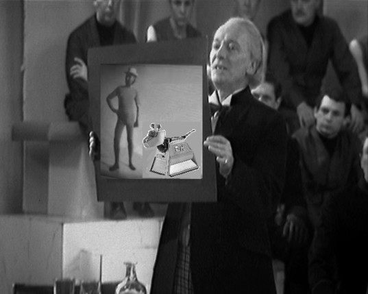 Hartnell's Dr Who, from The Keys Of Marinus, holding up a picture in court, over which Hartnell in a bathing costume standing next to K9 has been pasted over it.